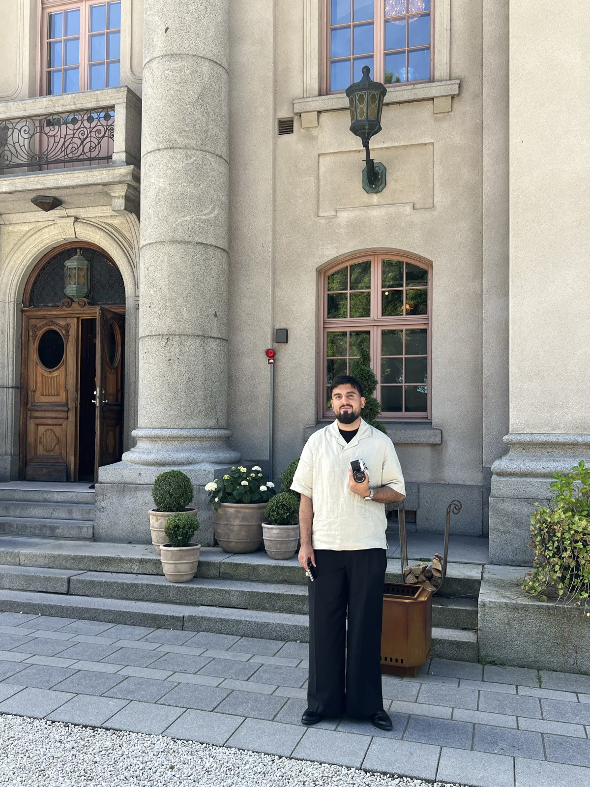 Zana Salman med en analog kamera i handen framför en äldre stenbyggnad